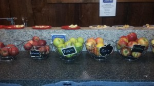 Many varieties of apples are on sale along with small pieces for tasting.