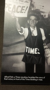 The newsboy holds up one of the famous Times headlines- The End of World War II.